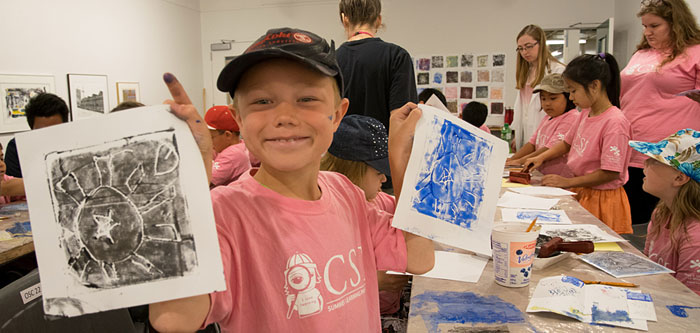 一个孩子拿着他在1c03画廊的艺术工作室里制作的两幅版画